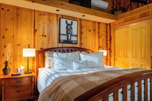 A wooden-paneled room with a bed, bedside lamps, a nightstand, a clock, and a framed picture on the wall. - Paso Wine Country • King Suite + Private Patio | Near Coast | Creekside Room (Paso Robles)