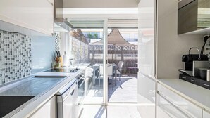 Eine moderne Küche mit Glastür, die auf eine Terrasse im Freien führt.