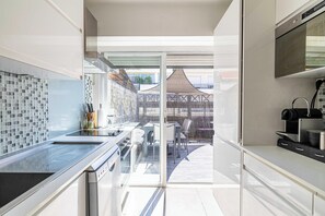 Eine moderne Küche mit Glastür, die auf eine Terrasse im Freien führt.