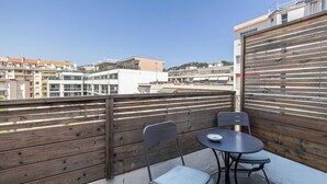 Ein Balkon mit Holzlattenzaun, zwei Stühlen und einem Tisch.