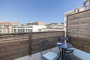 Ein Balkon mit Holzlattenzaun, zwei Stühlen und einem Tisch.