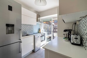 Eine moderne Küche mit Edelstahlgeräten, einem Wasserspender und Blick ins Freie.