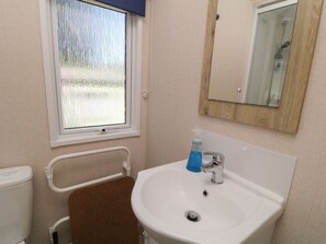 Ein Badezimmer mit einem weißen Waschbecken, einem Spiegel und einem Fenster mit Blick auf eine verschneite Landschaft.