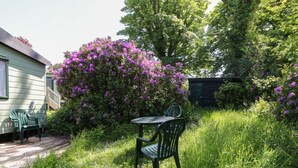 A garden with a table and chairs, surrounded by lush greenery and purple flowers. - Laughter Tor (Tavistock)
