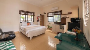 A compact hotel room with a bed, a desk, a chair, a sofa, and a kitchenette. - Lynhapartment Cochinchine (Ho Chi Minh City)