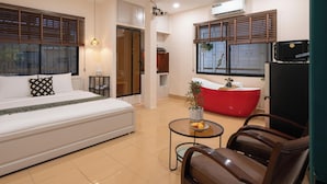 A hotel room with a bed, a red bathtub, a small table with fruit, and a TV. - Lynhapartment Cochinchine (Ho Chi Minh City)