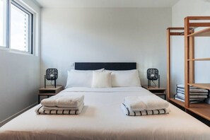 A neatly made bed with two towels, a dark headboard, and two bedside tables with fans. - LUX 2BD/2Bath Condo - ONE Mambo Beach 1 by Bocobay (Willemstad)