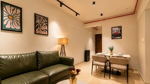 Una sala moderna con un sofá de cuero, una mesa de comedor con sillas y obras de arte en las paredes.