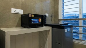Una kitchenette compacta con microondas, un refrigerador pequeño y una ventana con vistas a la ciudad.