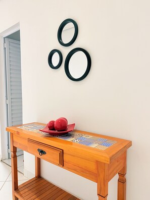 A wooden console table with a patterned tabletop, a drawer, and a decorative plate with red spherical objects. - Apartment in Urban São Paulo | 9 Minutes from Vila Sônia Station (São Paulo)