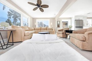 A modern living room with a large sectional sofa, a round coffee table, and a ceiling fan. - Heated Pool • Jacuzzi-Fire Pit - Mini Golf - Game (Pinellas County)