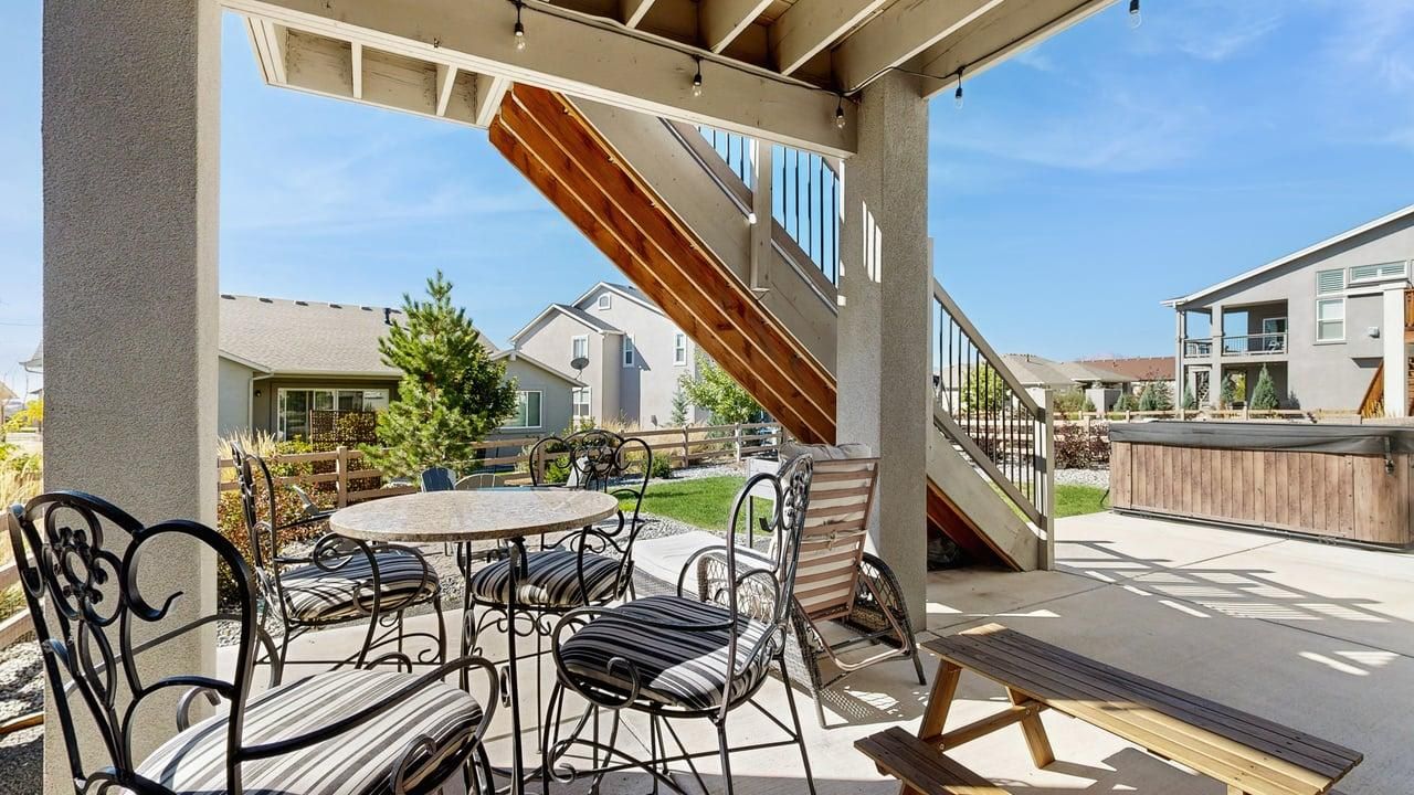 An outdoor patio area with a round table and chairs, a wooden bench, and a staircase leading to an upper level.
