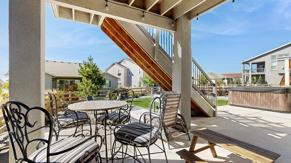 An outdoor patio area with a round table and chairs, a wooden bench, and a staircase leading to an upper level.