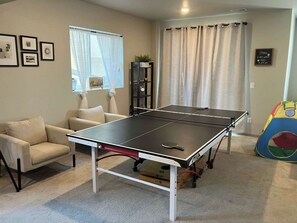 A ping pong table in a room with a sofa, a bookshelf, and a colorful play tent. - Elevated Escape- Spacious 5BR Colorado Springs House with Hot Tub and Mountain Views (Colorado Springs)
