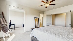 Ein Schlafzimmer mit einem Bett, einem Deckenventilator, einem Sessel und einem Schreibtisch.