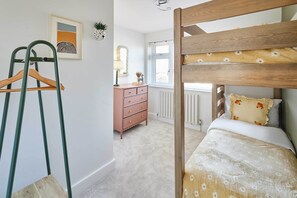 A bedroom with a bunk bed, a dresser, a mirror, and a radiator. - Host Stay Sandmoor (Whitby)