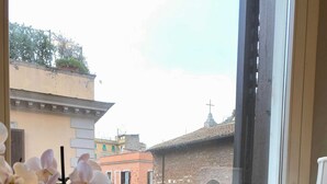 A window with a view of a historic stone bridge and buildings, a vase with a figure, and a desk with a picture frame and pens. - Chic Rome Apartment Master Bonus Study Bedroom (Rome)