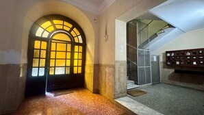 An interior corridor with a large arched doorway leading to a stairwell. - Chic Rome Apartment Master Bonus Study Bedroom (Rome)