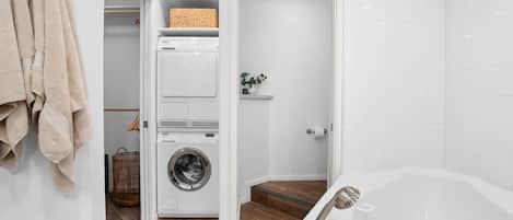 Une salle de bain moderne dotée d’un lave-linge et d’un sèche-linge intégrés, d’une douche à l’italienne et d’une baignoire sur pieds.