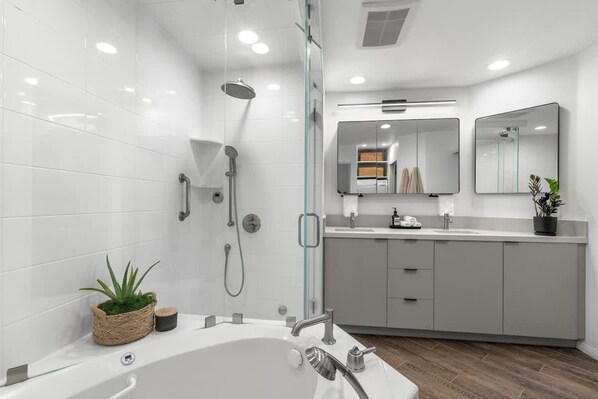 A modern bathroom with a bathtub, shower, and vanity with a mirror. - Oceanfront AC Fully Remodeled Unit (Solana Beach)
