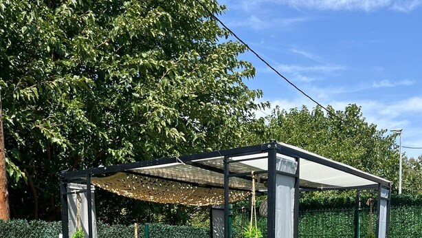 A gazebo with a table and chairs, surrounded by a green hedge and trees. - The Magical Village - 5 minutes from the beach (Calonge)