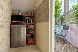 A compact kitchen with a stainless steel refrigerator, a microwave, and a small shelf with kitchenware. - Charming Studio on a Farm with Shared Pool, Summer Kitchen, and Wi-Fi (Jau-Dignac-et-Loirac)