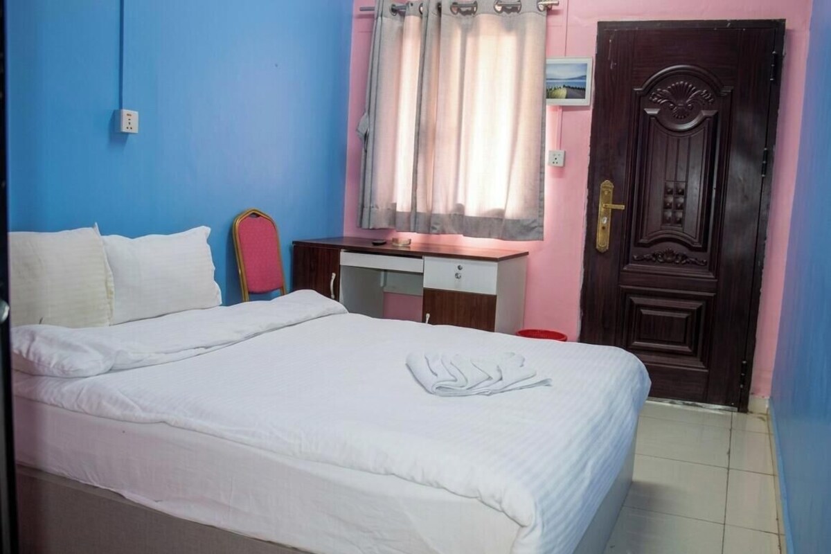 A bedroom with a bed, a desk, and a door.