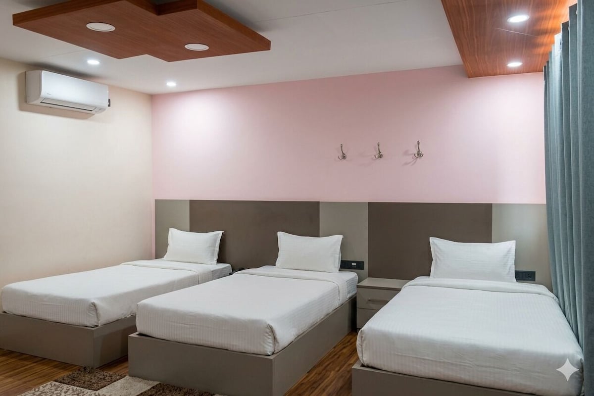 A hotel room with three single beds, a wooden ceiling, a wall-mounted air conditioner, and a light-colored rug.