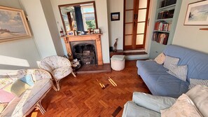 A living room with a fireplace, a sofa, a chair, and a bookshelf. - Observatory Apt - Historic Bedford Apt With Pool (Bedford)