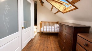A room with a wooden crib, a dresser, and a skylight. - Observatory Apt - Historic Bedford Apt With Pool (Bedford)
