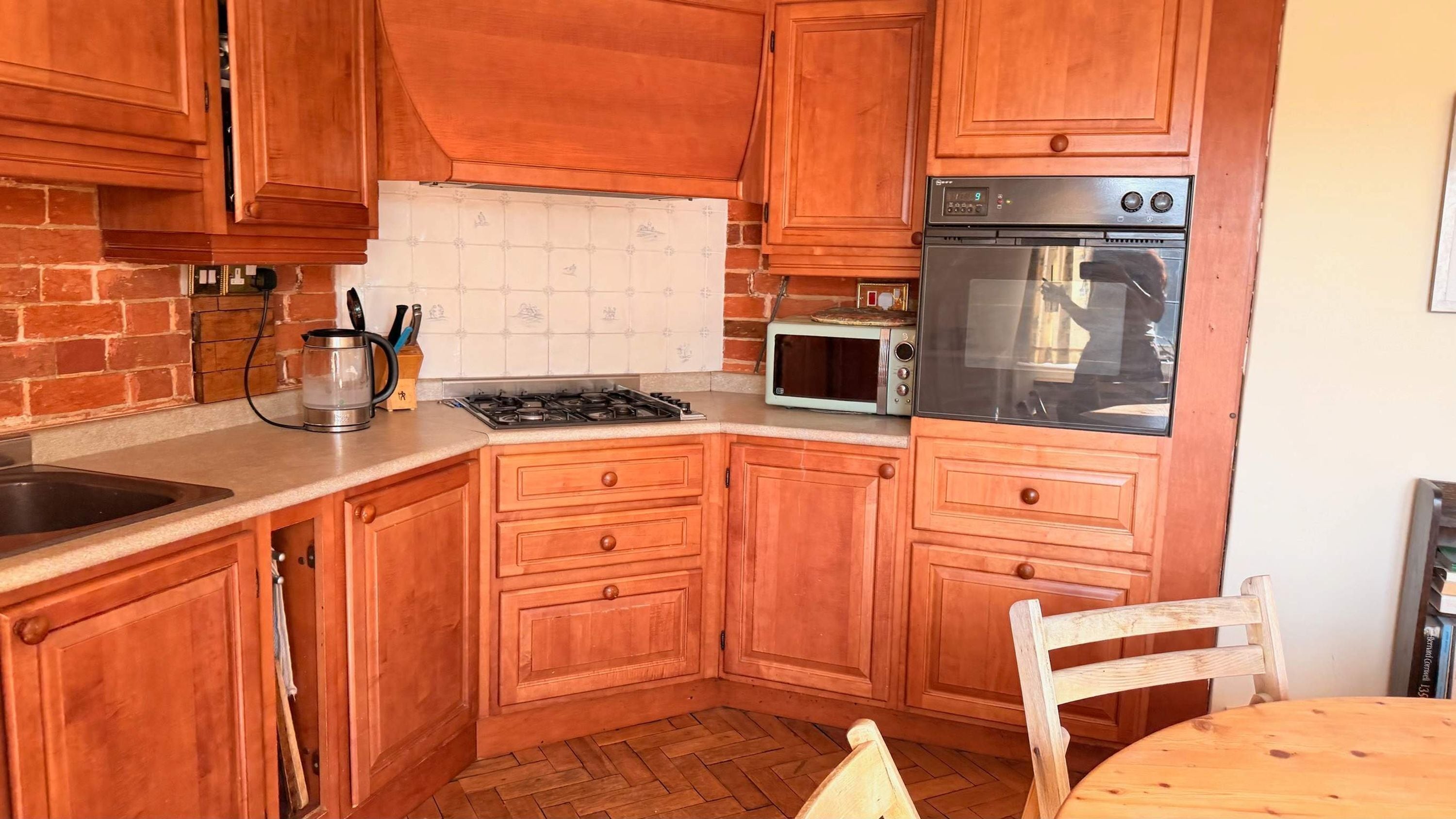 A kitchen with wooden cabinets, a gas stove, a microwave, and a stainless steel oven.