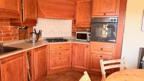 A kitchen with wooden cabinets, a gas stove, a microwave, and a stainless steel oven. - Observatory Apt - Historic Bedford Apt With Pool (Bedford)