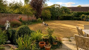 A garden with a statue, a cow, and a brick wall. - Observatory Apt - Historic Bedford Apt With Pool (Bedford)