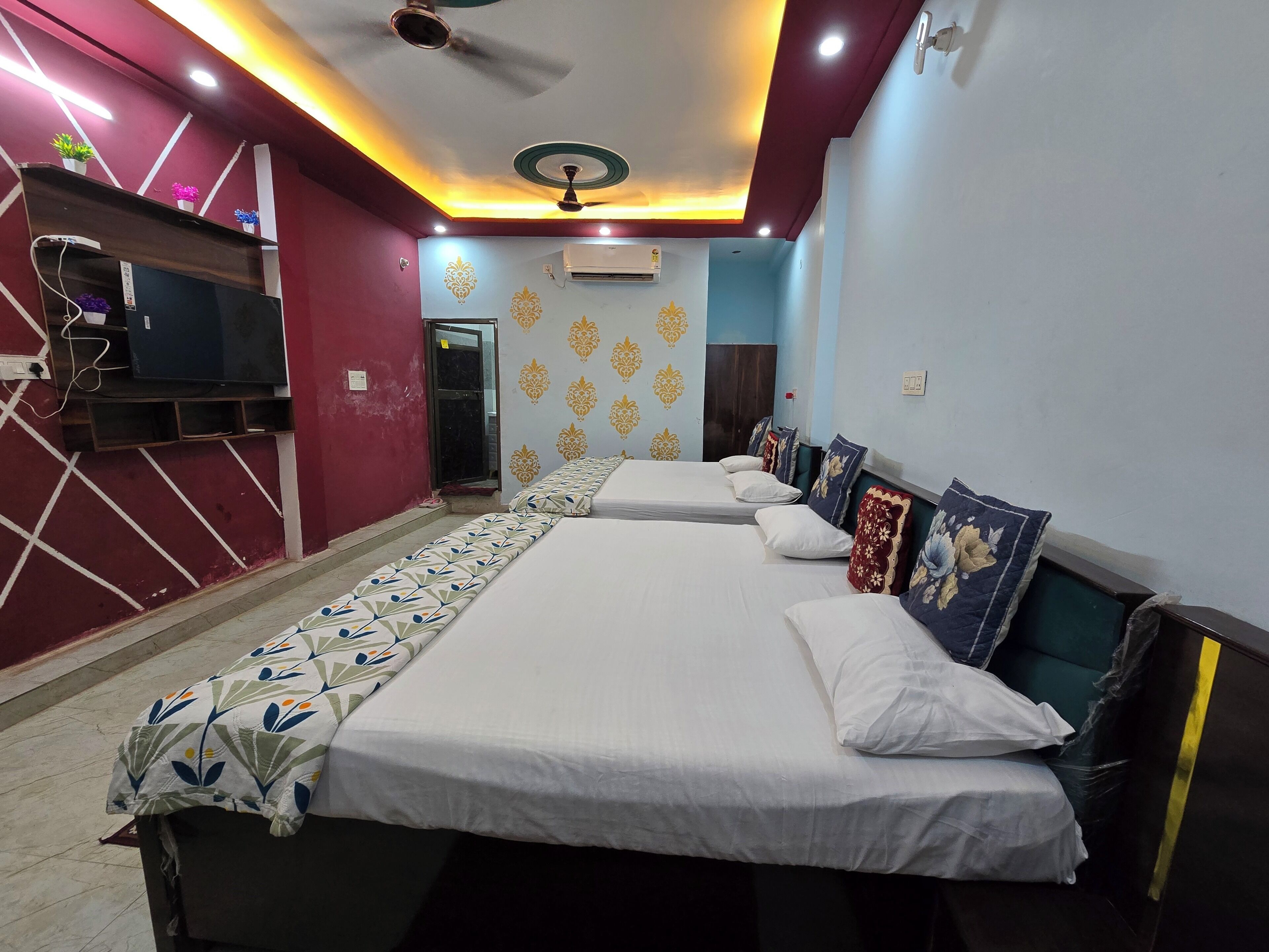 A hotel room with a long bed, a ceiling fan, and a TV on a stand.