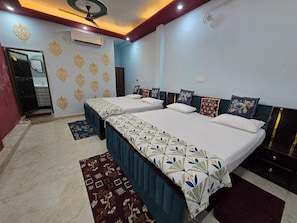 A hotel room with two beds, a ceiling fan, an air conditioning unit, and a bathroom with a mirror and sink. - VIP Inn (Ayodhya)