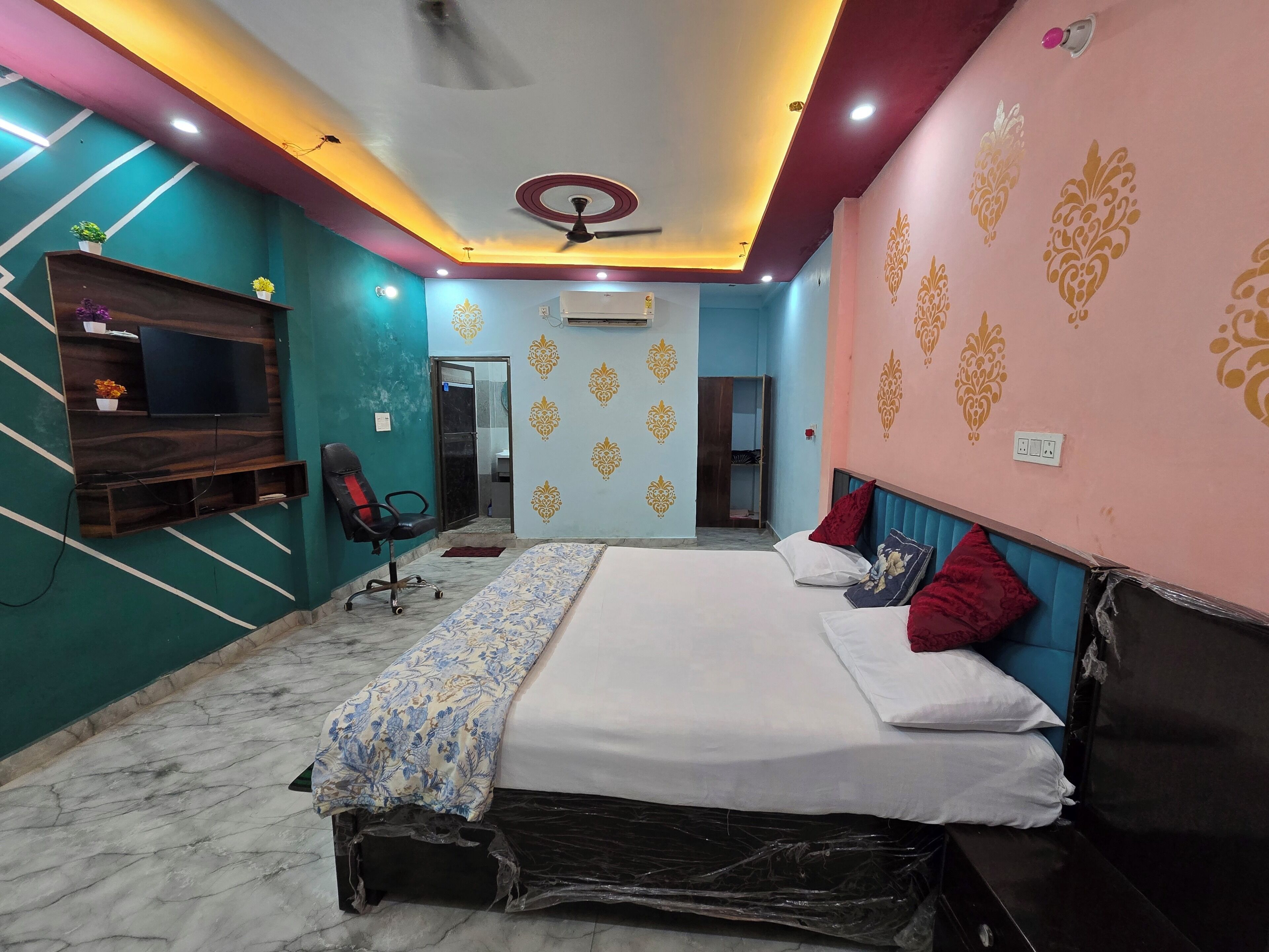 A bedroom with a bed, a desk, a chair, and a television.