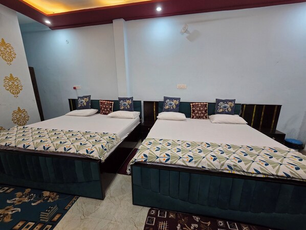 A hotel room with two beds, each with a patterned bedspread, a headboard, and a nightstand. - VIP Inn (Ayodhya)