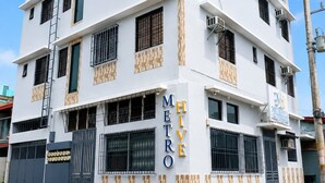 Un edificio de varios pisos con fachada blanca, múltiples balcones y un cartel que indica que es un hotel.