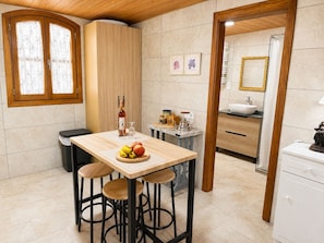 A kitchen with a wooden table, stools, a bottle, and a fruit bowl. - Juan De Dios Farmhouse (Cómpeta)