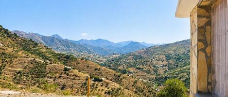 A mountainous landscape with terraced fields and a building with a stone facade.