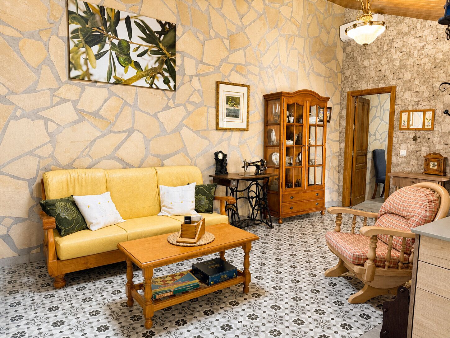 A cozy room with a stone wall, a yellow sofa, a wooden cabinet, and a patterned floor.