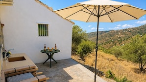 Un patio al aire libre con una mesa, sillas y una sombrilla.