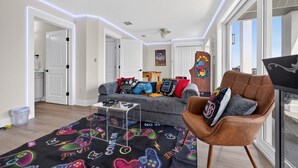 En moderne stue med sofa, et gaming-gulvtæppe og en læderlænestol.
