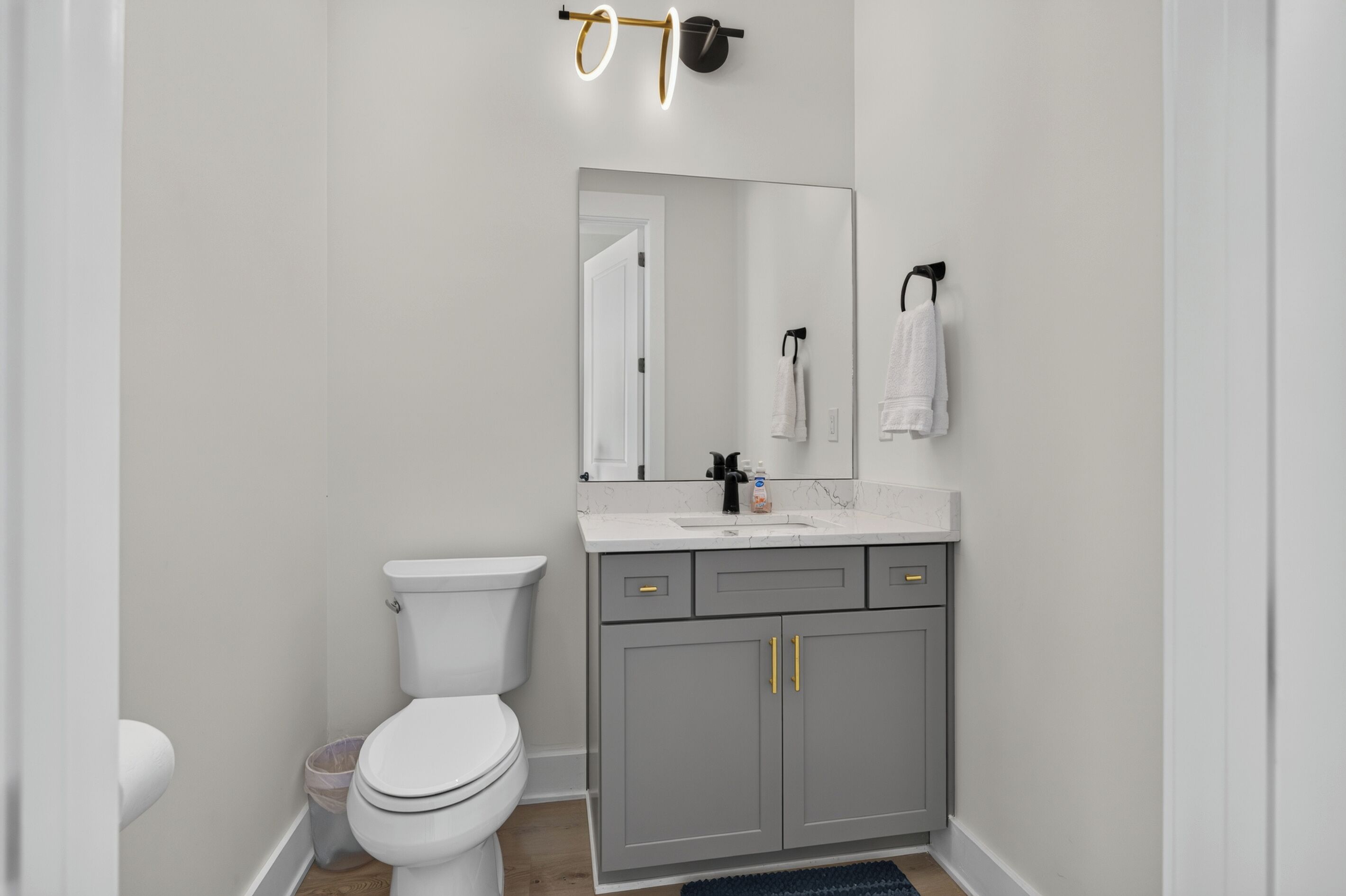 A modern bathroom with a toilet, sink, and mirror.