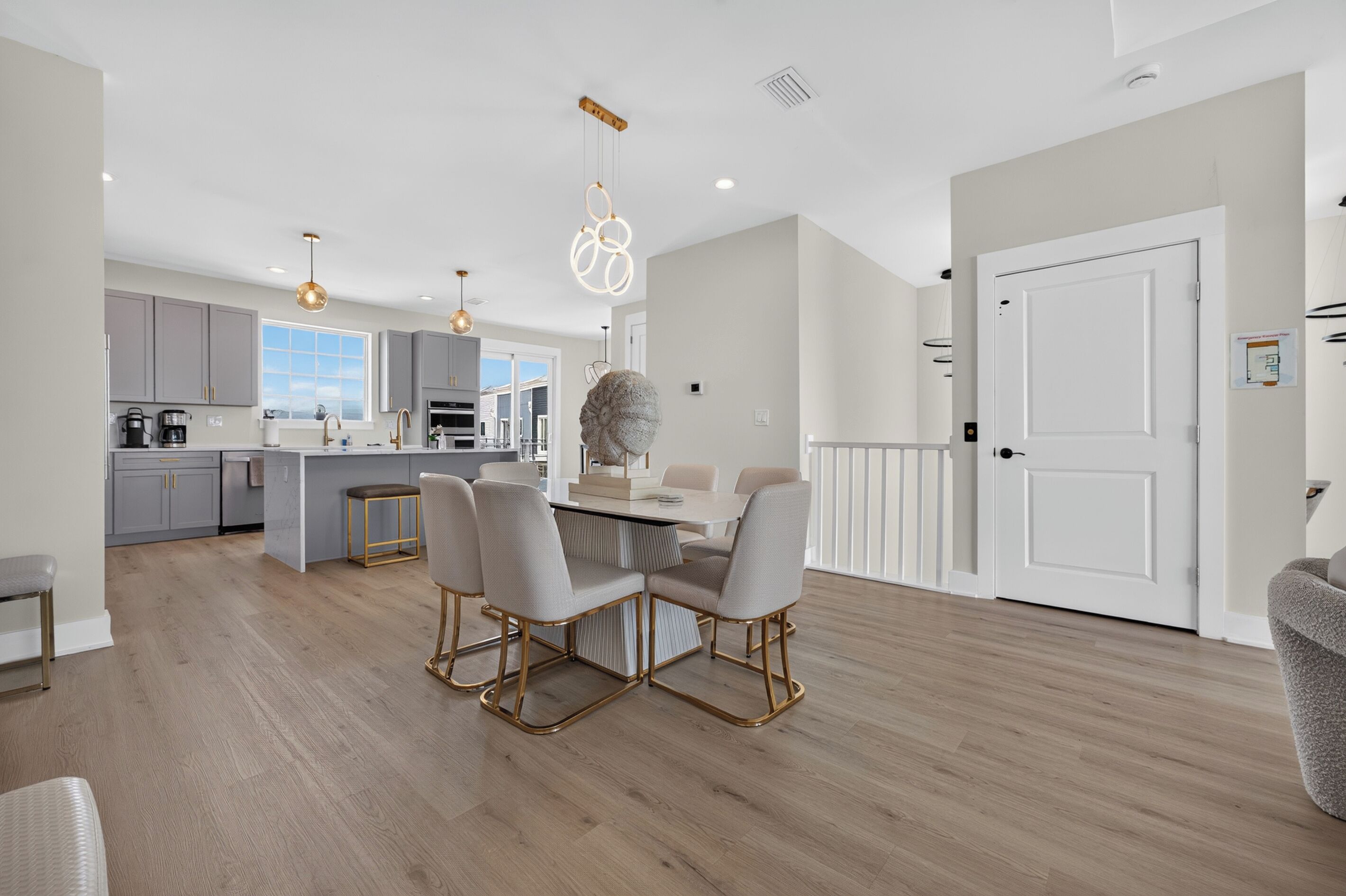 A modern kitchen with grey cabinets, a central island, and pendant lighting.