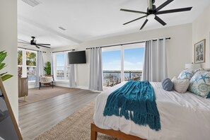 A bedroom with a bed, a ceiling fan, a TV, and a view of the outdoors. - Three-Story Home | Boat Slip | Walk Downtown (Saint Augustine)