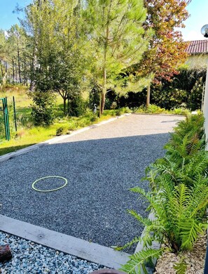 A gravel driveway leading to a house with a fenced garden area. - Villa Seignosse: A Beach Vacation (Seignosse)