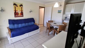 A compact living space with a sofa, a dining table, and a television. - T2 RDC avec jardin - LACANAU OCÉAN (Lacanau)
