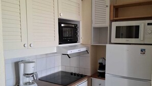 A compact kitchen with a built-in microwave, a coffee maker, and a dishwasher. - T2 RDC avec jardin - LACANAU OCÉAN (Lacanau)