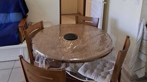 A dining area with a round table, six chairs, a hanging light fixture, and a door in the background. - T2 RDC avec jardin - LACANAU OCÉAN (Lacanau)